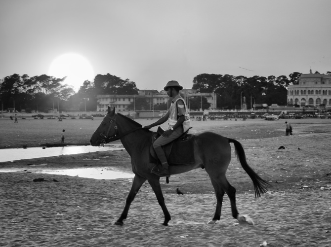 A cop from Horse Mounted Police battalion on his patrol, while Sun is setting opposite to the Marina Beach, Chennai, India.