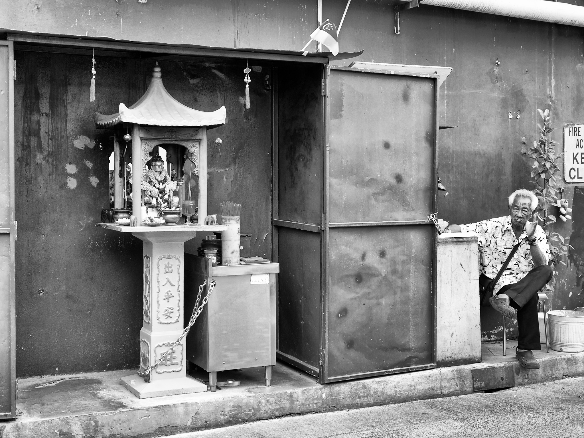 A gatekeeper beside the street-side makeshift temple for four faced Brahma (Phra Phrom), Bugis Street, Singapore