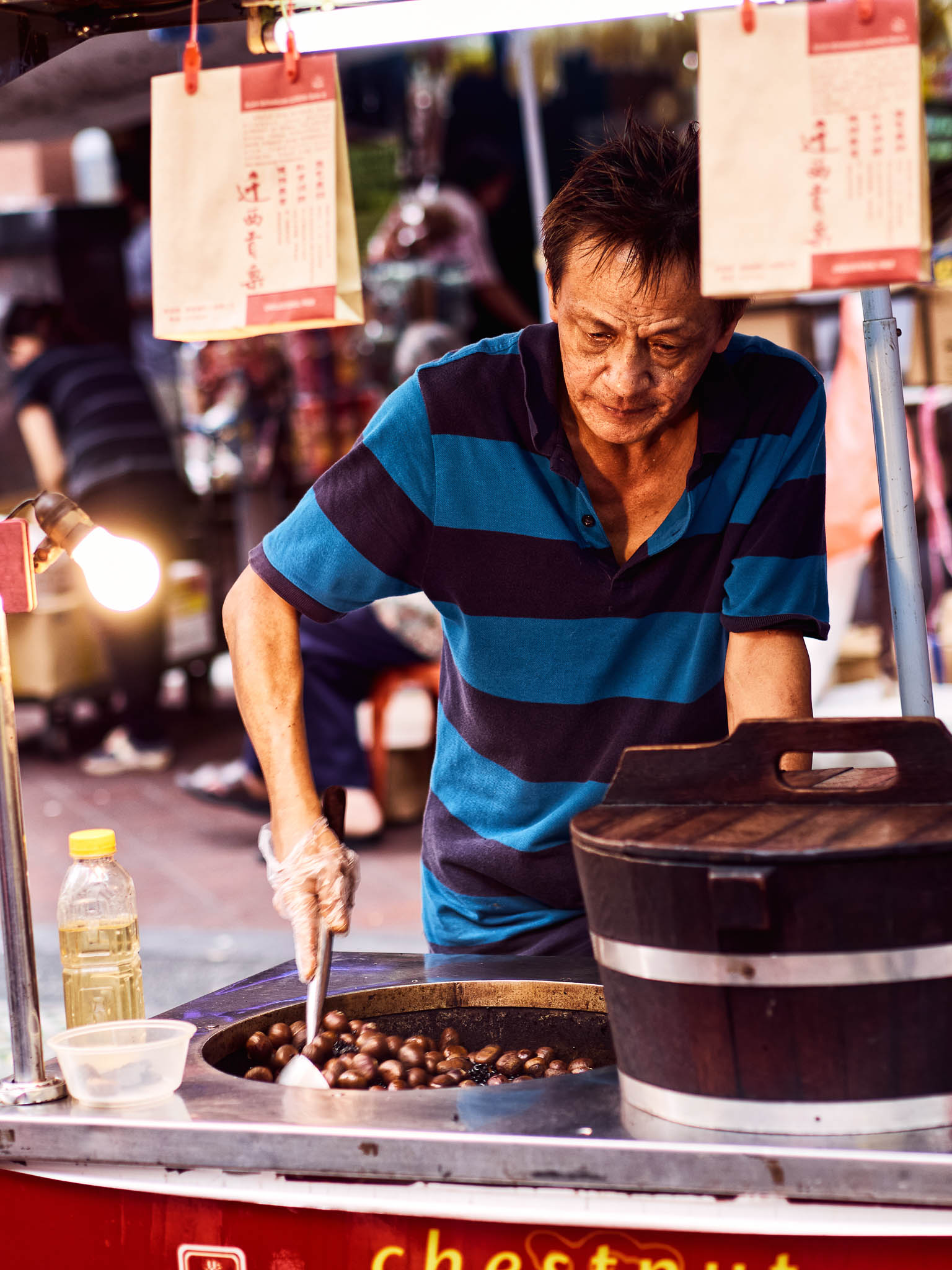 A street vendor, roasting chestnuts at his mobile shop, Paya Lebar, Singapore