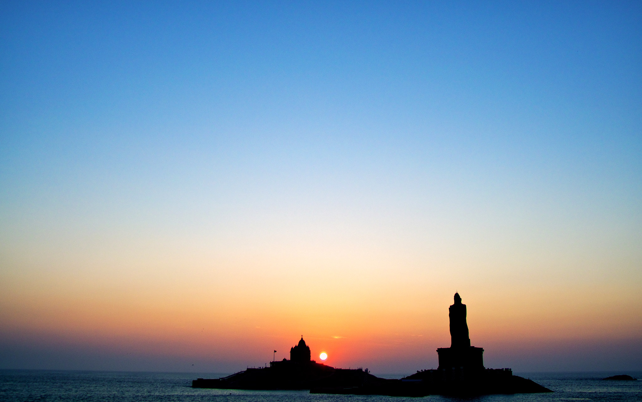Sunrise over the confluence of three oceans (Bay of Bengal, Arabian Sea and Indian Ocean) behind the Thiruvalluvar Statue and Vivekananda rock, Kanyakumari, Tamil Nadu, India